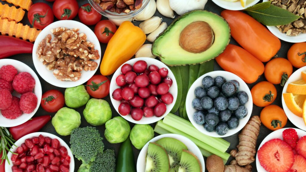 Alimentos frescos y nutritivos como aguacate, frutos rojos, verduras, nueces y cítricos relacionados con una alimentación saludable para la circulación.